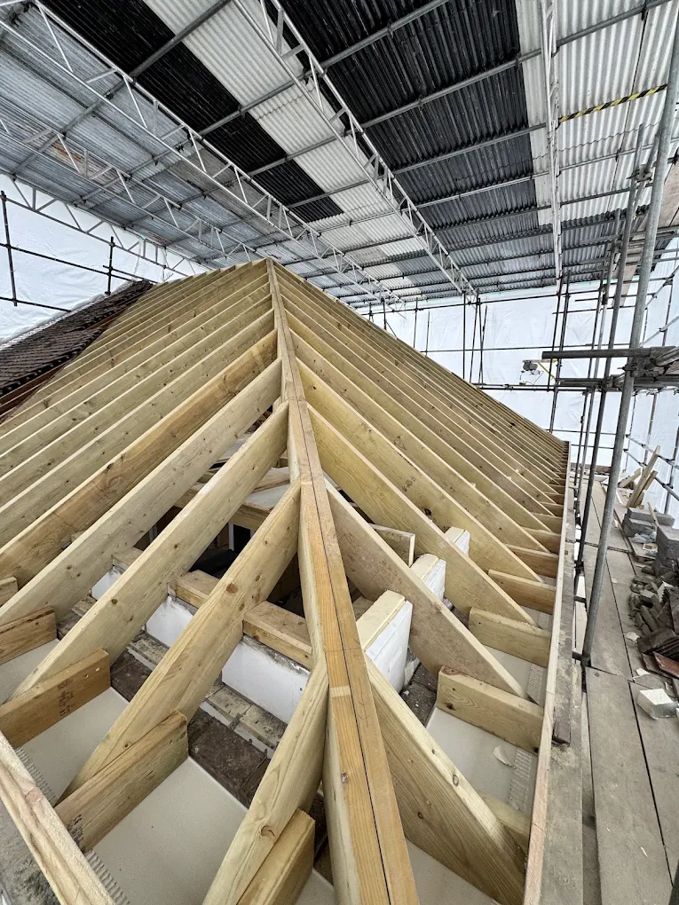 Roof structure timber frame under construction, rafters and hip framing fitted ahead of roof covering