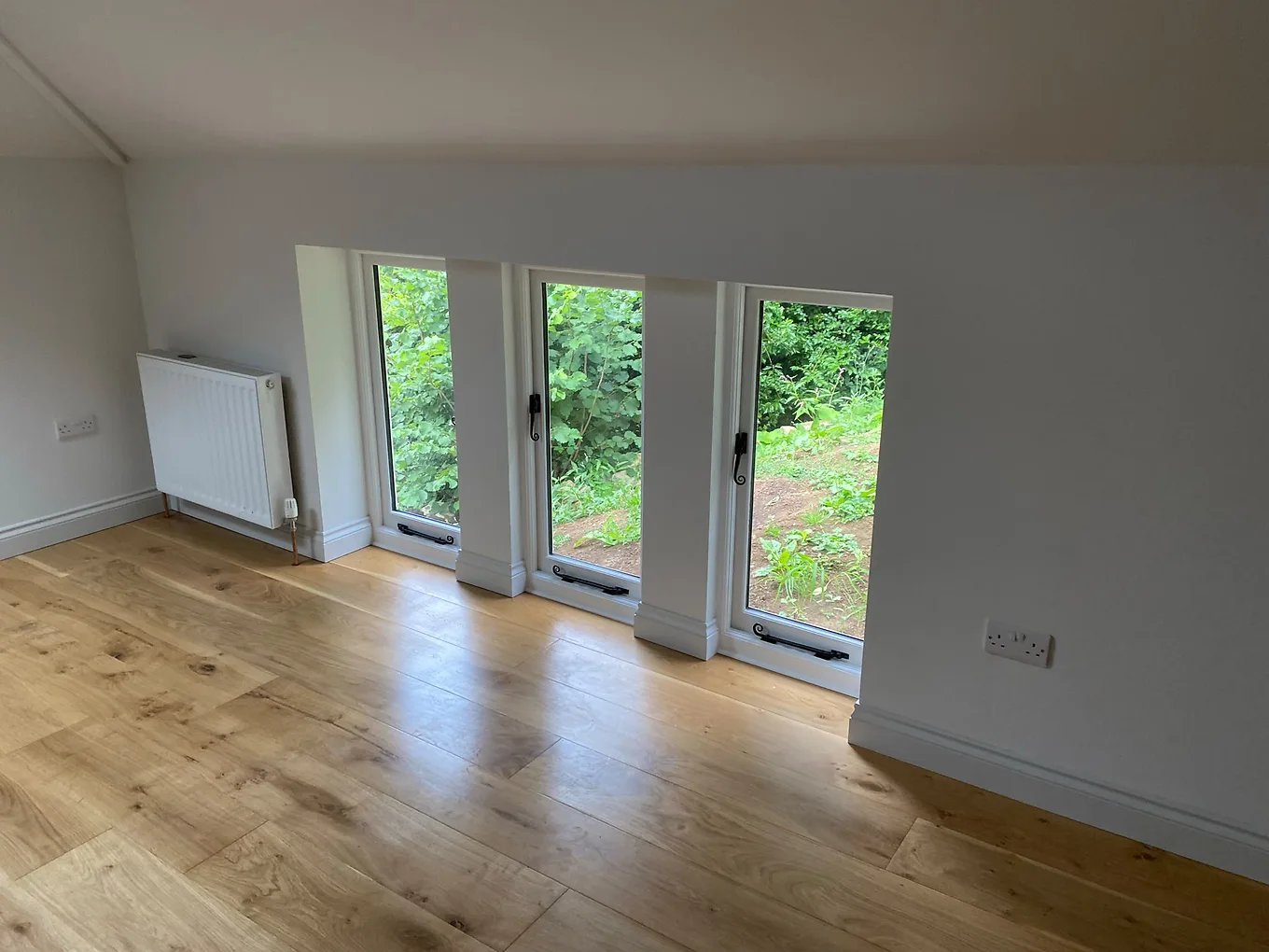 Finished engineered oak flooring in a bright room with white skirting boards, ready for handover