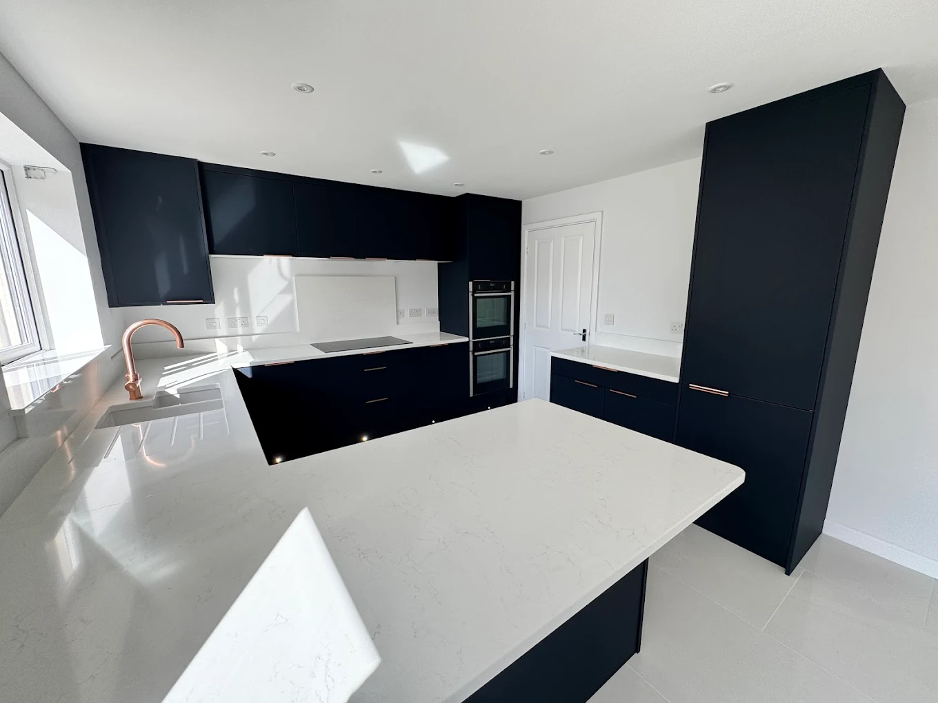 Gloss white kitchen with full-height units and integrated handles