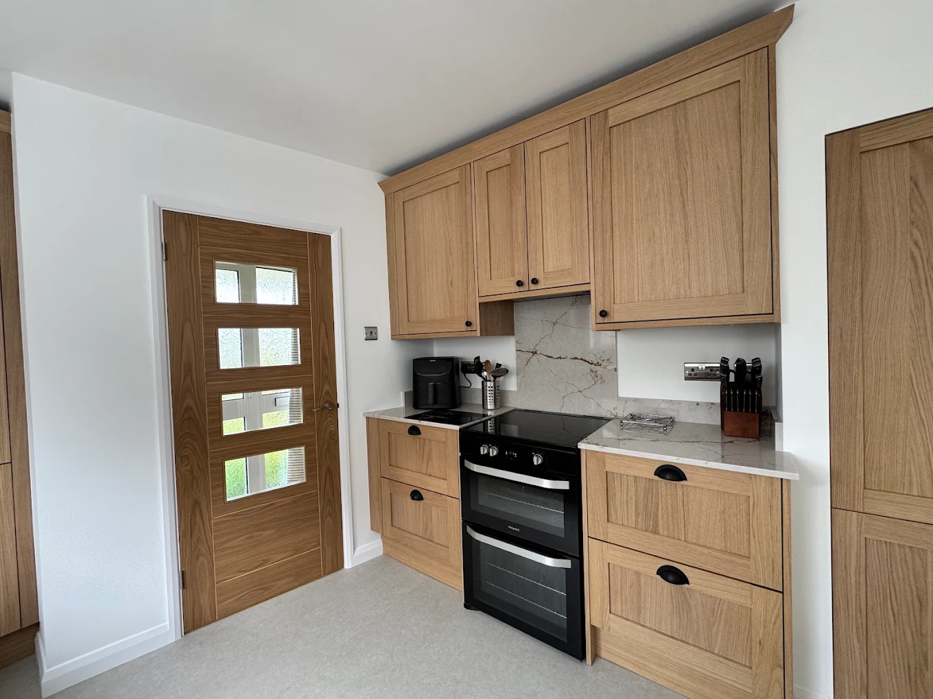 Dark navy shaker kitchen with quartz worktops and brass cup handles