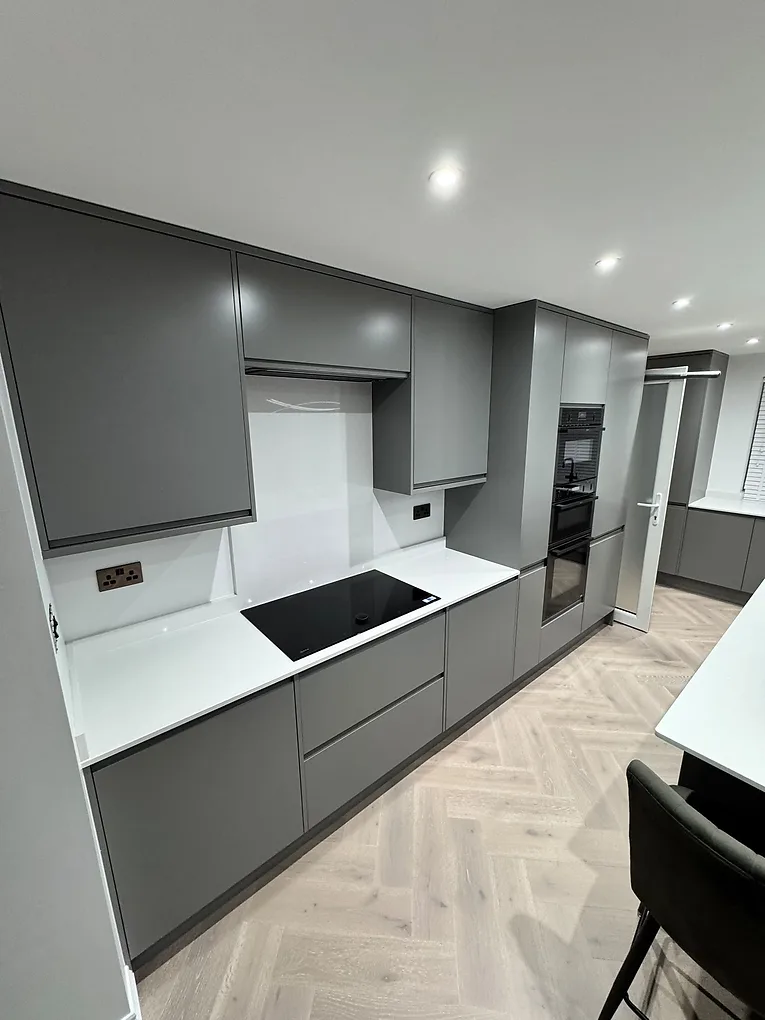 Handleless matte grey kitchen with a black induction hob and integrated Neff ovens